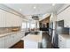 Well-lit kitchen with an island cooktop, white cabinets, and a view into the living room and dining area at 15407 E Crestline Pl, Centennial, CO 80015