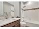 Bright bathroom featuring a shower over tub, white tile with decorative accent stripe, modern vanity with a large mirror at 11950 Mosey Ct, Parker, CO 80138