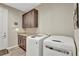Laundry room with white front-load washer and dryer, gray counter tops, and wood cabinets at 11950 Mosey Ct, Parker, CO 80138