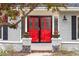 Close-up of a vibrant red front door with decorative glass, framed by brick columns and fresh flowers at 5440 W Hinsdale Ave, Littleton, CO 80128