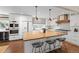Open kitchen with a large wooden island, modern appliances, and black wire bar stools at 5440 W Hinsdale Ave, Littleton, CO 80128