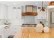 Bright kitchen with white cabinets, a wooden vent hood, and a butcher block island at 5440 W Hinsdale Ave, Littleton, CO 80128