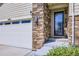 Close-up of the front door and garage showcasing the stone and siding details at 6863 E 132Nd Pl, Thornton, CO 80602