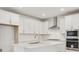 New kitchen design features white cabinets, a stainless steel range hood and subway tile at 8229 Butte Creek St, Littleton, CO 80125