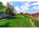 Lush backyard featuring a well-maintained lawn, landscaping, fire pit, and wooden fence at 2474 Ravenswood Ct, Longmont, CO 80504