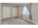 A bedroom with gray walls, carpeted floor, window with curtains, and double closets at 2474 Ravenswood Ct, Longmont, CO 80504