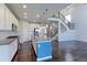 Open kitchen with modern stainless appliances, a blue island with granite countertops, and dark hardwood floors at 2474 Ravenswood Ct, Longmont, CO 80504