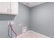 A laundry room featuring tile floors, blue-gray walls, cabinets, and washer/dryer hookups at 2474 Ravenswood Ct, Longmont, CO 80504