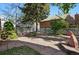 Landscaped backyard featuring a patio, stone accents, lush trees, and privacy fence at 618 S Franklin St, Denver, CO 80209
