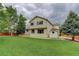 Back exterior featuring lush lawn, mature trees, and a two-story home at 14910 Williams St, Thornton, CO 80602