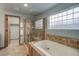 Well-lit bathroom featuring a soaking tub, glass block window, and walk-in shower for a spa-like experience at 14910 Williams St, Thornton, CO 80602