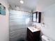 Cozy bathroom with a striped shower curtain, dark vanity, and mirrored medicine cabinet at 413 Jamaica St, Aurora, CO 80010