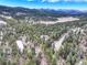 The property is located in a heavily wooded area with a long driveway, and distant mountain views at 9299 William Cody Dr, Evergreen, CO 80439