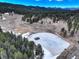 An aerial shot over open land shows a frozen pond and evergreen trees at 9299 William Cody Dr, Evergreen, CO 80439
