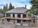 The back of the property features a large wooden deck with black metal railings, and a ground-level patio area at 9299 William Cody Dr, Evergreen, CO 80439