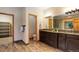 A bathroom with double sinks, wood-look tile floors, and a doorway leading to another room at 9299 William Cody Dr, Evergreen, CO 80439