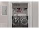 A modern laundry room with two front-load washer and dryer units and shelving for storage solutions at 9318 Las Ramblas Ct # R, Parker, CO 80134