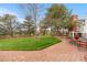 Picturesque backyard with a paver patio, lush lawn, mature trees, and split rail fencing at 15020 Harrison St, Brighton, CO 80602
