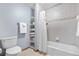 Cozy bathroom with a toilet, bathtub, shower, and storage shelves for added functionality and organization at 15020 Harrison St, Brighton, CO 80602