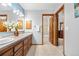 Bright bathroom featuring a double sink vanity, wood cabinets, and open doorway to the shower and closet at 15020 Harrison St, Brighton, CO 80602