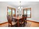 Dining room with wood table, six chairs, chandelier, and natural light streaming through the large windows at 15020 Harrison St, Brighton, CO 80602