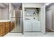 Laundry room with stainless refrigerator and washer/dryer unit, offering shelving for organization and storage at 7877 S University Way, Centennial, CO 80122
