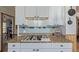A detailed view of the kitchen gas range, featuring white cabinets and colorful backsplash at 576 S Tabor St, Elizabeth, CO 80107