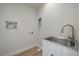 Bright laundry room featuring a stainless steel sink, white cabinets, and modern fixtures at 1372 Lowell Blvd # 4, Denver, CO 80204