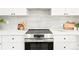 Modern kitchen with stainless steel oven and cooktop with white cabinets and neutral backsplash at 4320 Lamar St, Wheat Ridge, CO 80033