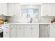 Well-lit kitchen featuring stainless steel dishwasher, white cabinets, backsplash, and modern faucet at 4320 Lamar St, Wheat Ridge, CO 80033