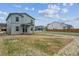 Back of light blue two-story house with unfinished backyard and other houses nearby at 2177 Flower Blossom Ave, Brighton, CO 80601