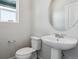Modern bathroom has a sleek pedestal sink, round mirror, and plenty of light at 2177 Flower Blossom Ave, Brighton, CO 80601