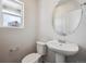 Powder room features a modern sink, oval mirror, toilet, and window at 2177 Flower Blossom Ave, Brighton, CO 80601