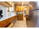 A compact kitchen featuring wood cabinets, tile countertops, and stainless steel appliances at 3021 Grape St, Denver, CO 80207