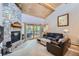 Cozy living room with a stone fireplace, wood ceiling, comfortable seating, and access to the balcony at 180 Broken Lance Dr # 14, Breckenridge, CO 80424