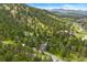 Overhead view of homes in a wooded area on a hillside, set against a backdrop of distant mountains at 1129 Genesee Vista Rd, Golden, CO 80401