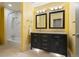 Bathroom with double vanity, black cabinets, granite counters, and shower over tub at 1129 Genesee Vista Rd, Golden, CO 80401