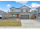 Charming two-story home featuring a covered porch, gray siding, red shutters, and a two-car garage at 27684 E Byers Ave, Aurora, CO 80018