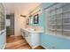 This primary bathroom features dual sinks, wood floors, and a stylish glass block window at 8095 E Lehigh Ave, Denver, CO 80237