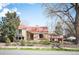 Charming brick home with a red roof, mature trees, and a wrought iron fence at 2084 Bell Ct, Lakewood, CO 80215