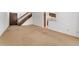 A large empty room with neutral carpet and stairway access to the second floor and an entrance at 2960 S Parker Ct, Aurora, CO 80014