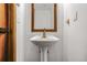 Elegant powder room featuring a pedestal sink with a wood-framed mirror and neutral wall color at 23646 Genesee Village Rd, Golden, CO 80401