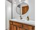 Bathroom boasting a wood vanity with white countertop, round mirror, and a shower with a curtain at 23646 Genesee Village Rd, Golden, CO 80401