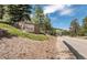 Stone entrance to The Village at Genesee, nestled among mature trees and landscaping at 23646 Genesee Village Rd, Golden, CO 80401