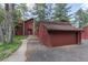 Charming two-story home with red siding and a two-car garage, surrounded by lush greenery and trees at 23646 Genesee Village Rd, Golden, CO 80401
