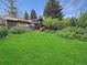 Expansive backyard featuring a greenhouse, lush green lawn, and mature trees at 9236 W Euclid Ave, Littleton, CO 80123
