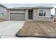 Charming single-story home featuring a modern front door, grey garage door, and a well-lit driveway at 6974 E 126Th Dr, Thornton, CO 80602