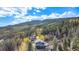 Stunning aerial view of a home surrounded by lush greenery and majestic mountains under a clear blue sky at 779 Aspen Way, Evergreen, CO 80439