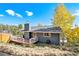 Charming single-story home with gray siding, a wooden deck, and scenic mountain views, under a clear blue sky at 779 Aspen Way, Evergreen, CO 80439