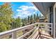 Wide angle of a wood deck with a white railing and view of surrounding forest at 779 Aspen Way, Evergreen, CO 80439